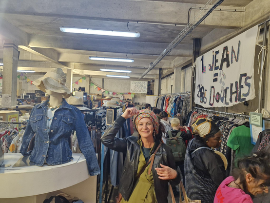 Au milieu des rayonnages de vêtements, la conseillère municipale au Droit des Femmes, Julie Muret, pose avec un foulard avec un grand sourire, pendant que des clients de la Ressourcerie examinent les rayonnages autour d'elle. 

Sur la droite de la photo, sur un grand drap blanc fixé au mur, la phrase : "1 jean = 285 douches".