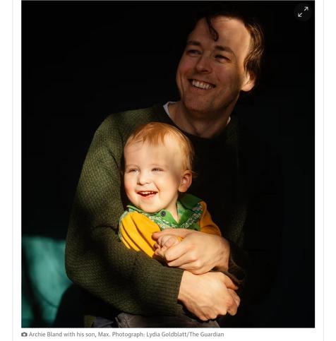 A screenshot of a photograph of a smiling man holding a smiling little boy in his arms. They are both looking off to the light coming in from the left. 
The text reads "Archie Bland with his son, Max. Photograph: Lydia Goldblatt/The Guardian"