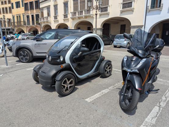 Photo of a Renault Twizy quadricycle parked next to a motor scooter.