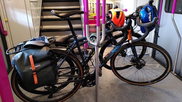 Sur une plateforme d'une voiture de RERC, 2 vélo appuyé sur la barbe centrale. Les casques accrochés aux guidons