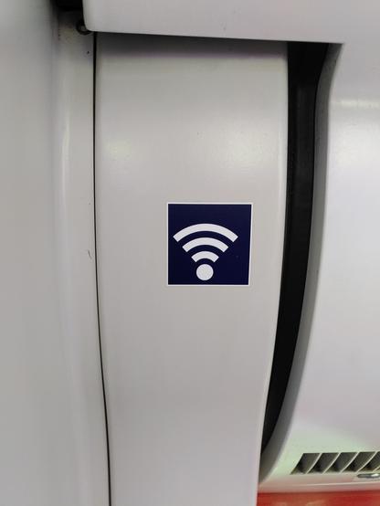 Ein kleines blaues Info-Schild für das WLAN in einer S-Bahn. Das Symbol ist nicht mittig im Schild sonder. Nach links unten versetzt.