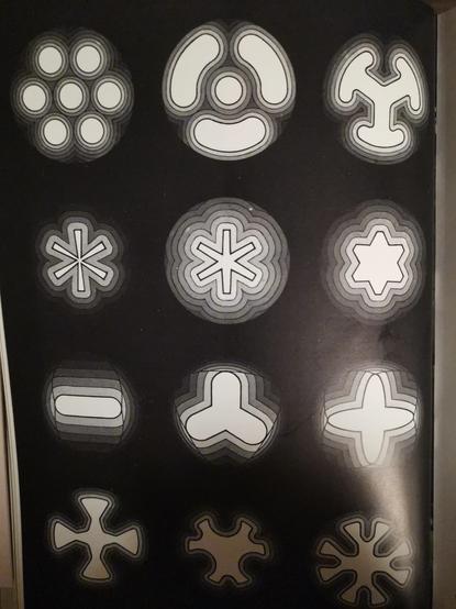 Image à fond noir montrant des formes géométriques blanches centrées : six points en hexagone, un astérisque, une croix grecque, etc.