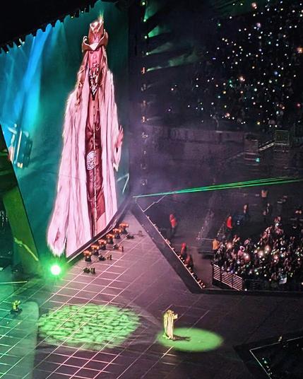 Beyoncé on stage in a glam cowgirl outfit and oversized fur coat, a green light shining on her