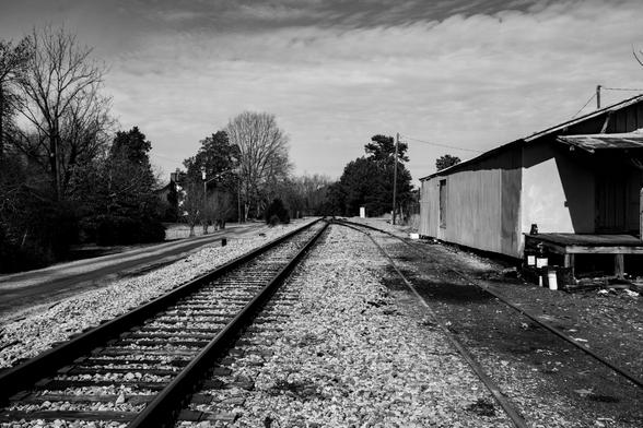 A road, a railroad track and a joining spur heading off into the distance.