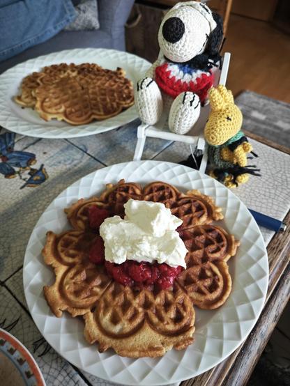 Snoopy und Woodstock genießen eine knusprige Waffel mit heißen Himbeeren und Sahne