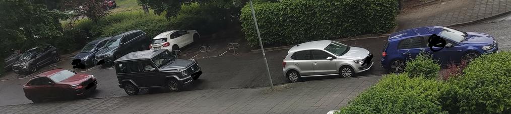 4 Autos in einer Privatstraße, parkend am Straßenrand in der Parkverbotszone. Links im Hintergrund private Parkplätze. Wer da runter oder drauf will, hat ein Problem.
