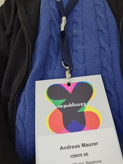 Re:publica25 Badge an einem blauen Lanyard, vor einem blauen Pullover. Aufschrift auf einem Aufkleber auf dem Badge: Andreas Maurer, IONOS SE,.... Public Relations