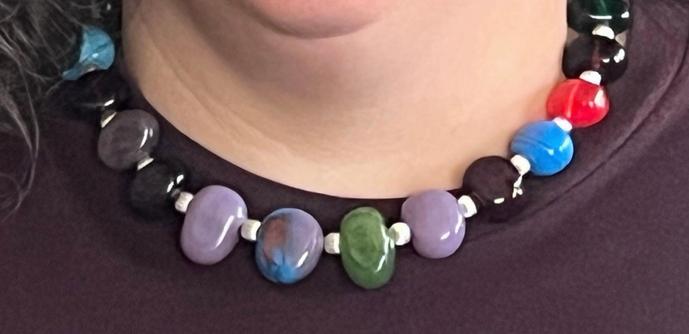 close up image of a light skinned woman wearing a multicolored handmade lampwork glass bead necklace.