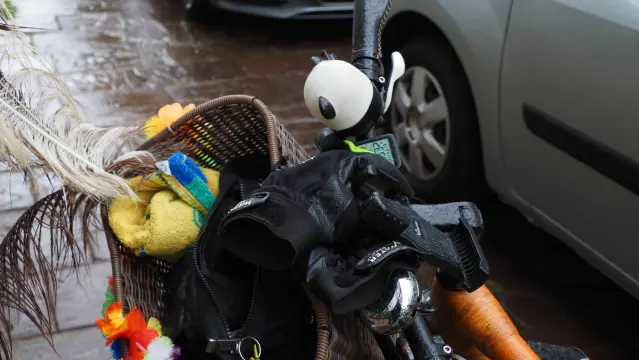 Gelbes Handtuch im Fahrradlenkerkorb. Im Hintergrund sieht man feuchten Bürgersteig