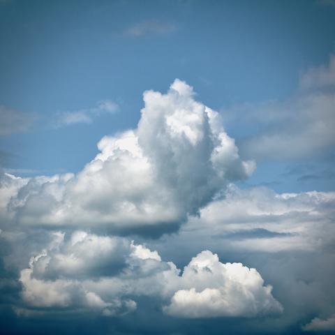 Bright white clouds fill most of a blue midday sky.