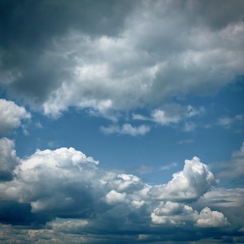 Bright white clouds fill most of a blue midday sky.