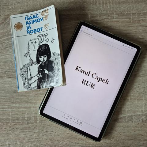 Obálky knih "Já robot" v papírové podobě a "RUR" na tabletu.