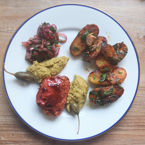 5 halbe Kartoffeln mit Kräutern, ein Pfeffermedaillon, ein Häufchen Zwiebel-Salsa, zwei Kleckse Erdnuss-Sauce und 2 Kapernbeeren auf dem Teller