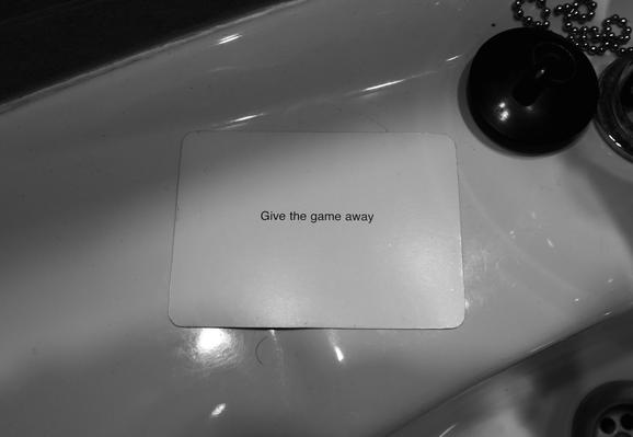 A black-and-white photo of an Oblique Strategy card. The card reads: 'Give the game away'.
