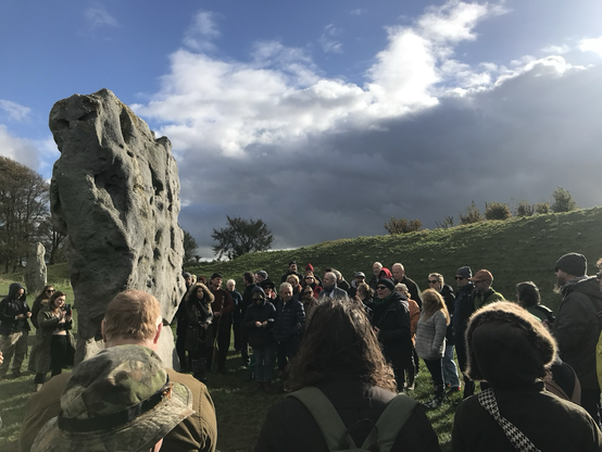 Forty people gathered around a stone at Avebury.