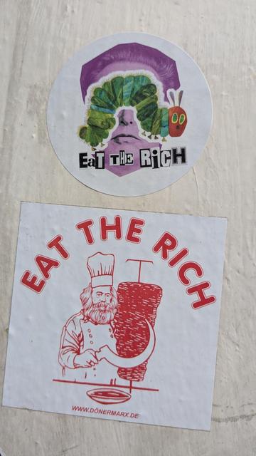 2 verschiedene Sticker mit dem Thema „eat the rich“ 1 mit der kleinen Raupe Nimmersatt und Elron Musk, der andere mit Karl Marx als „Dönermann“ im klassischen Logodesign am Drehspieß mit Sichel als Messer.