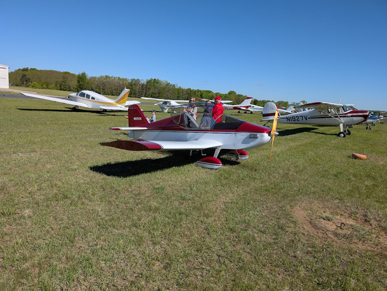 A small single seat experimental Sonex aircraft in red and white colors parked on the flight line.