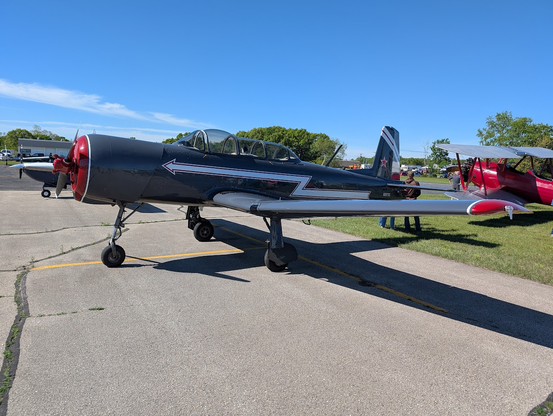 I am unsure the aircraft, it looks similar to various WWII airframes and specifically the T-6. It is a dark grey with a white arrow bolt from back to front.