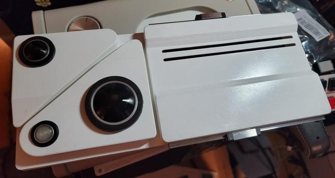 A 3D model replica of the baseline scanner from Blade Runner 2049. A white vertical base with 2 dark lenses and one white lens on the left It is missing the vertical scanner on the right so you can see the two linear rails.
