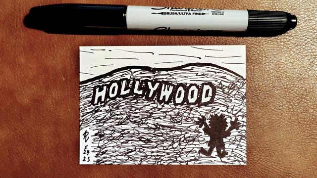 Marker drawing of the hill containing the famous Hollywood Sign. In silhouette further down the hill, the Muppet character Sweetums raises his arms in triumph. The drawing is signed with my "RV" signature glyph and dated 5-24-25. The black marker used to draw the image rests on the table above the card.