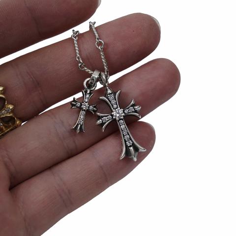 Hand showing two chrome hearts diamond-encrusted cross pendants on a chain