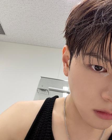 selfie of Seungmin wearing a black tank top and a silver chain necklace, showing half of his face