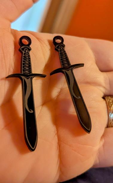 Two sword shaped earrings in black plastic/acrylic.