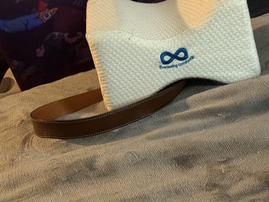 A belt and a sleep pillow (for between your legs) together on a bed