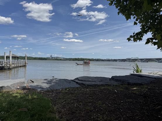 The image depicts a serene riverside scene on a sunny day. In the foreground, there is a grassy area with a few large rocks and a wooden dock extending into the water on the left side. The water is calm, reflecting the blue sky with scattered white clouds. A small boat with a red canopy is visible in the center of the river, moving away from the dock. In the background, a bridge spans the river, connecting two land masses. On the right side, a tree with green leaves frames the scene, adding a natural element to the composition. The sky is mostly clear with a few wispy clouds, and a bird is flying in the upper part of the image. The overall atmosphere is peaceful and inviting, with a mix of natural and man-made elements.

Provided by @altbot@fuzzies.wtf, generated privately and locally using Ovis2-8B

🌱 Energy used: 0.183 Wh