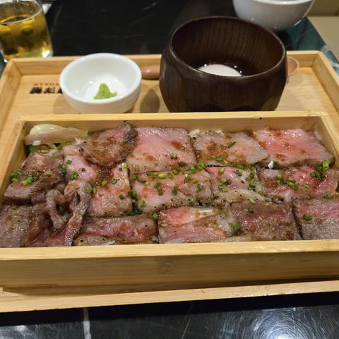 A box of A5 wagyu on rice with some chopped scallions on top