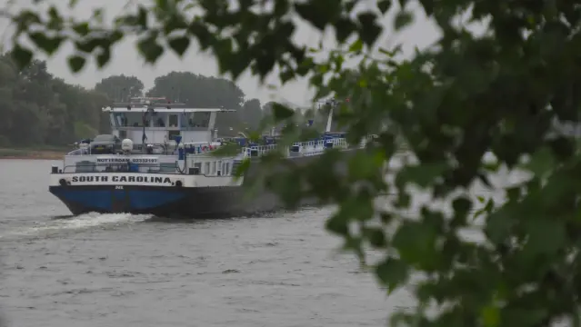 Frachtschiff auf dem Rhein. Auf dem Heck steht ein PKW