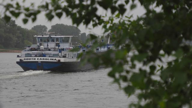 Frachtschiff auf dem Rhein. Auf dem Heck steht ein PKW