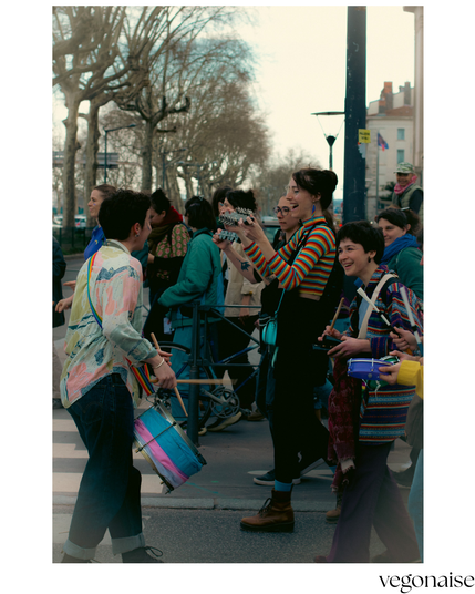 photo de 3 personnes dans une fanfare au milieu de la manif. Elles se démarquent par leurs habits colorés et leurs sourires