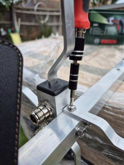 Close up of a small screwdriver being prevented from accessing the screw vertically by the vertical radiator