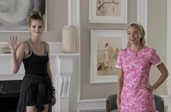 Meghann Fahy and Milly Alcock in a beautiful room with expensive art on the walls. One is dressed in shorts and a tank top looking like discount store goods and the other is in an expensive dress.