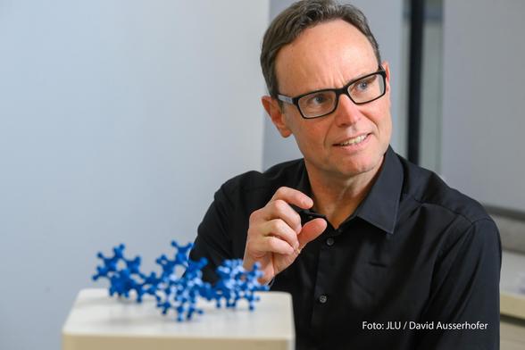 Prof. Peter Schreiner mit einem blauen Molekülmodell.