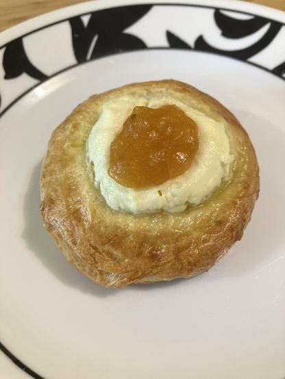 A round golden pastry with cream cheese and apricot jam in the middle.
