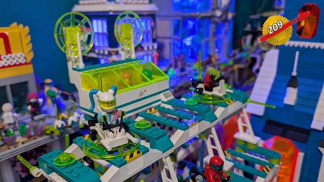 Man sieht ein aus neongelben, türkisen, weißen und Limettenfarbenen Klemmbausteinen gebaute Kommandozentrale und ein Landefeld. Futuristisch angehaut. Es handelt sich um ein modifiziertes Set aus dem Jahre 1983.