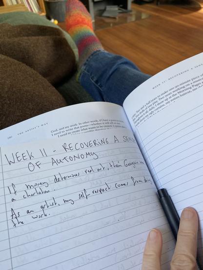 Een schrift met aantekeningen op schoot. Er staat “Week 11 - recovering a sense of autonomy”