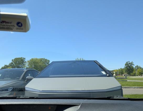 Nose to nose with a cyber truck in a parking lot under a blue sunny sky.