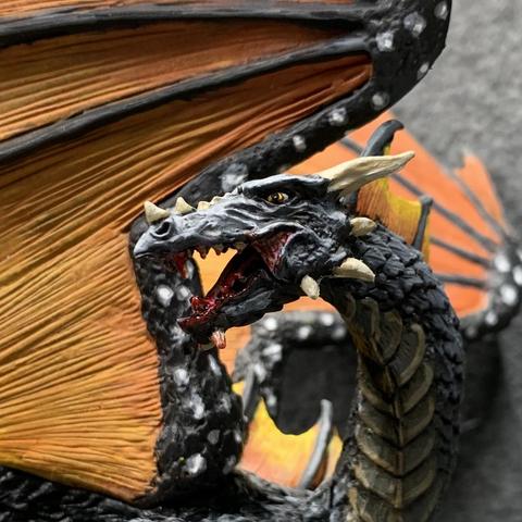 A black dragon with orange and yellow wings like a monarch butterfly. The wings are held upwards, and its tail wraps around its front. It has an open mouth with gore dripping from it.