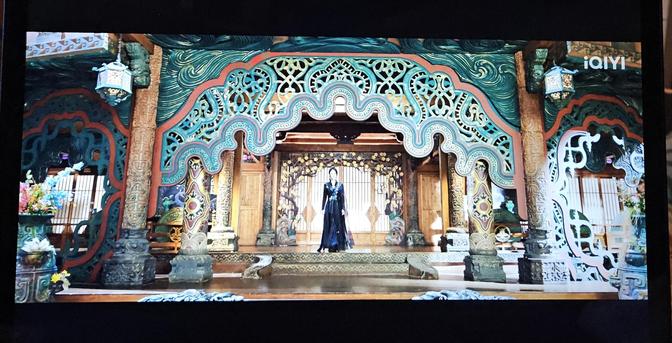 It's hard to describe the set in full, because everything is decorated and carved, from the pillars with character medallions and enamel flowers, to the lanterns with their lattice screens and flower tips, to the ceiling screens with lace like panels with brushed turquoise colour. Master Tian stands on a podium with carved blooming trees behind her back, looking like she's about to deliver a speech that will change the millenium.