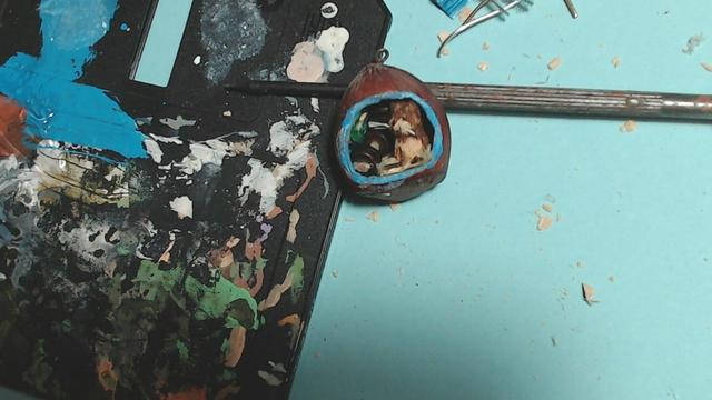un pendentif noisette avec dedans, un chat, un altère et un paquet de chips