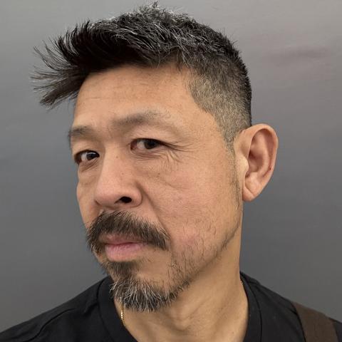 A selfie from the neck up. I’m wearing black t-shirt. My face is turned 45° so you could see my very short hair on the sides.