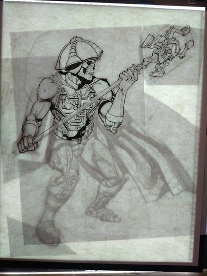 A half-finished ink drawing of Skeletor as he appeared in The New Adventures of He-Man. The drawing is being illuminated from the back by a light-pad and you can see the preliminary drawing made-up of cut-and-taped scraps of paper underneath the heavy bristol paper on top.