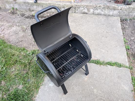 A small smoker grill packed with charcoal and burning the paint off. Cooking soon.