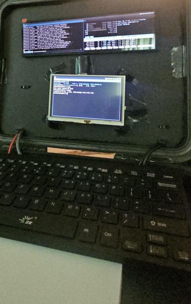 A plastic storage container with foam core inside the lid and two displays. One display is ultrawide format 19x5 and one beneath it is 16x9. Wires run to the bottom half where there is a keyboard and trackpad.