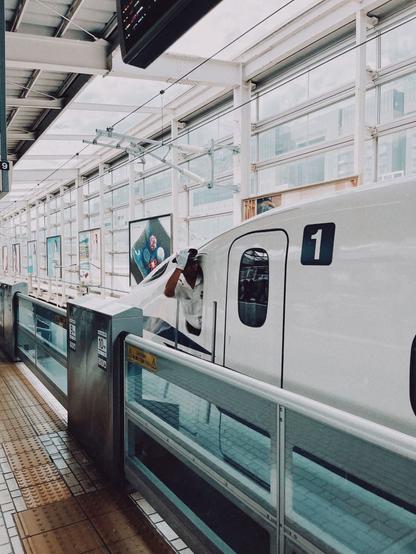 A train leaving the station with a person hanging out the window