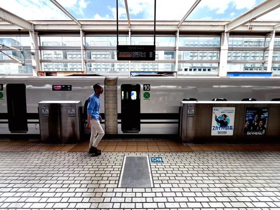 A person walks in front of a train in the station awaiting passengers to disembark and embark on