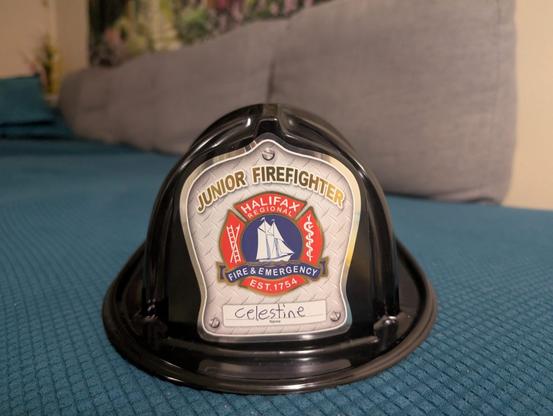 A plastic firefighter helmet with the words Junior Firefighter and the name Celestine written on it.